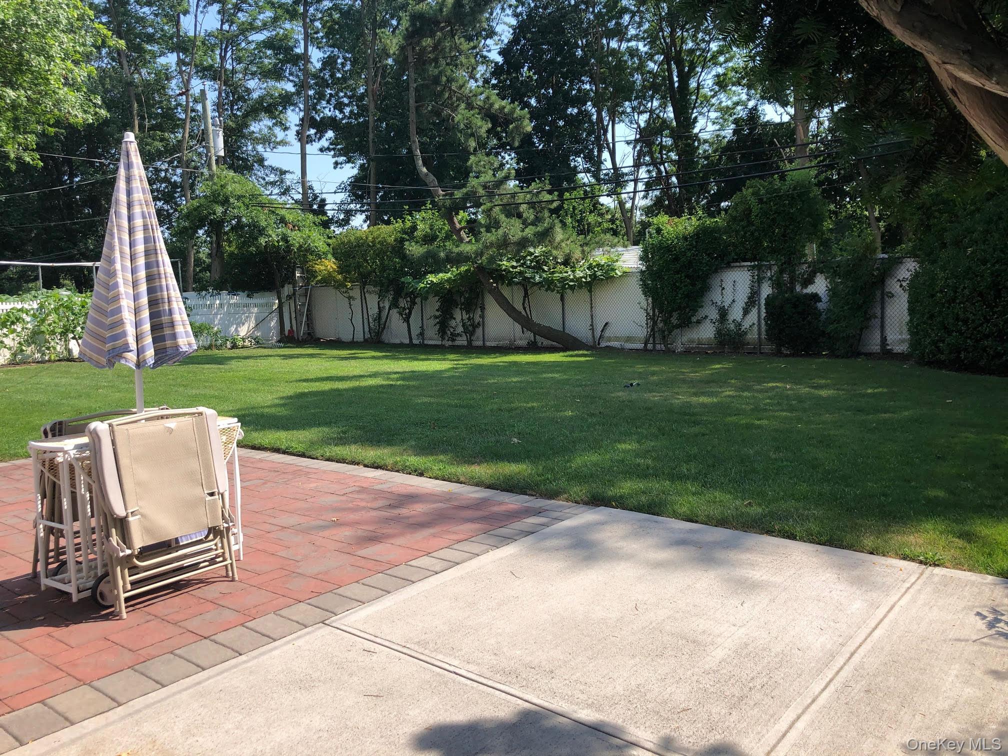 69 Soundview Road Great Neck, NY 11020 - Photo 4 of 8 a view of a backyard with table and chairs and a small yard