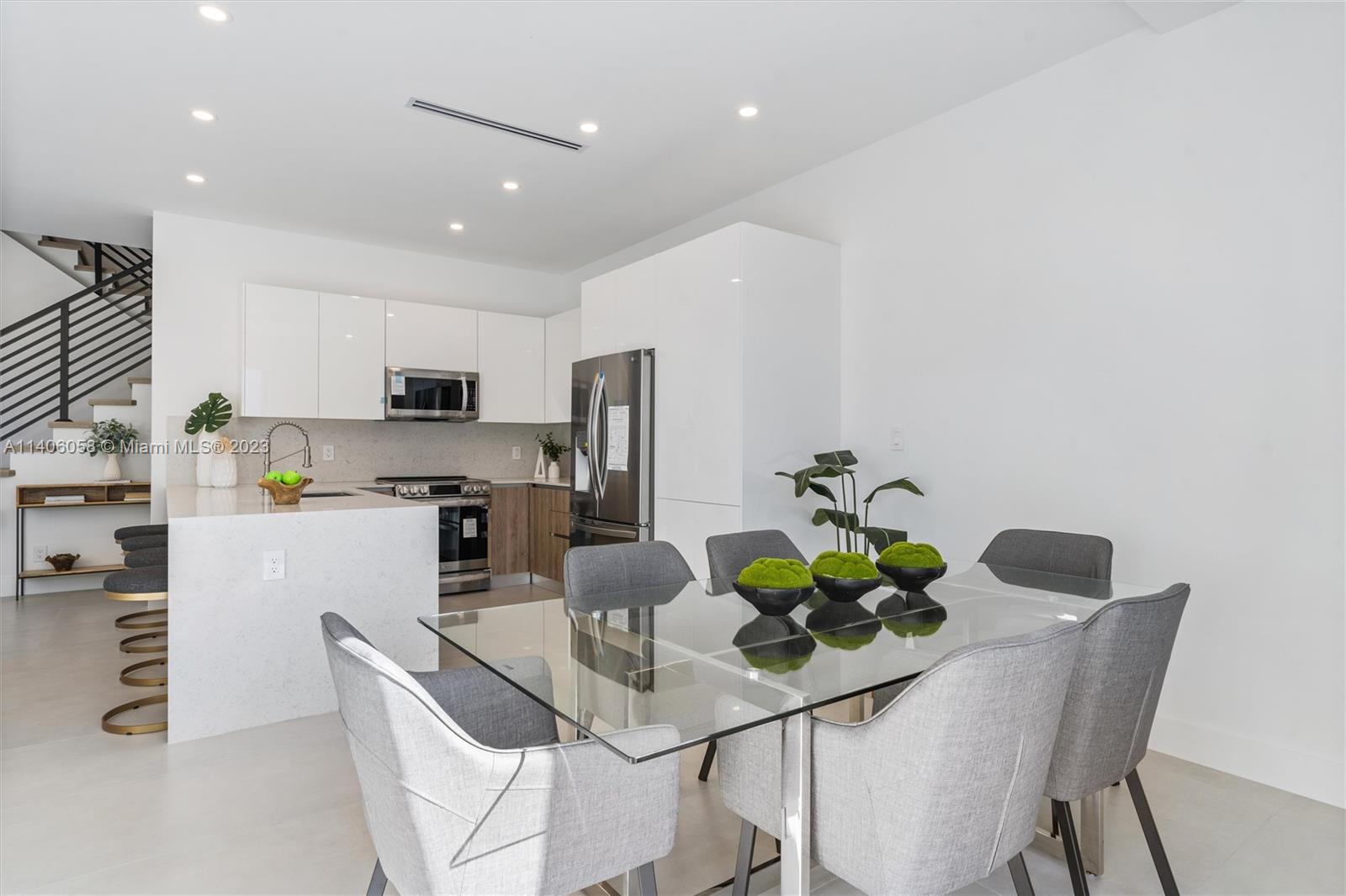 2290 Southeast 6th Street Pompano Beach, FL 33062 - Photo 7 of 22 a kitchen with stainless steel appliances a dining table chairs and white cabinets