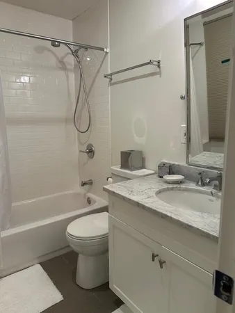 a bathroom with a granite countertop sink a toilet and shower