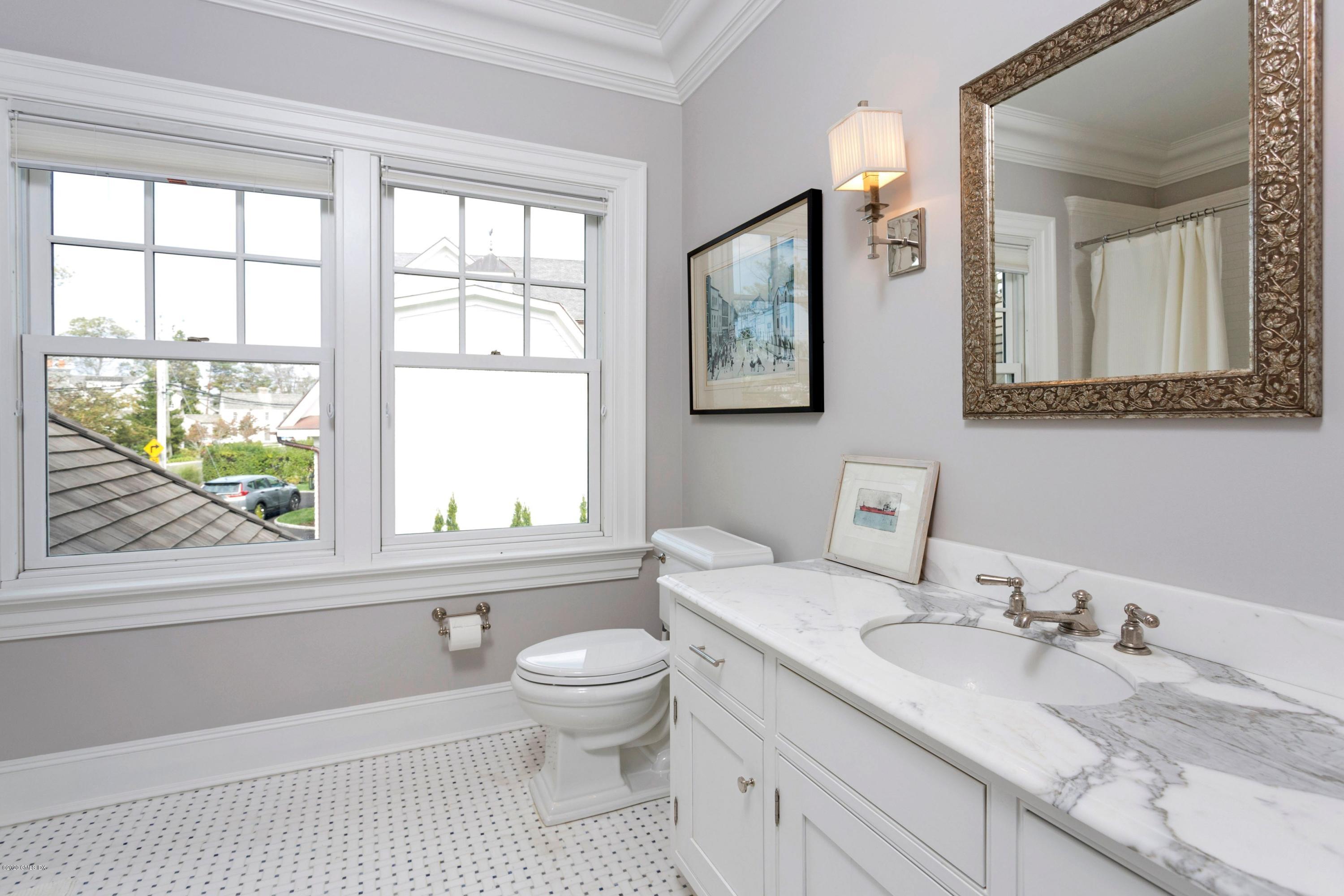 186 Shore Road Old Greenwich, CT 06870 - Photo 25 of 37 a bathroom with a granite countertop sink toilet a large mirror and a window