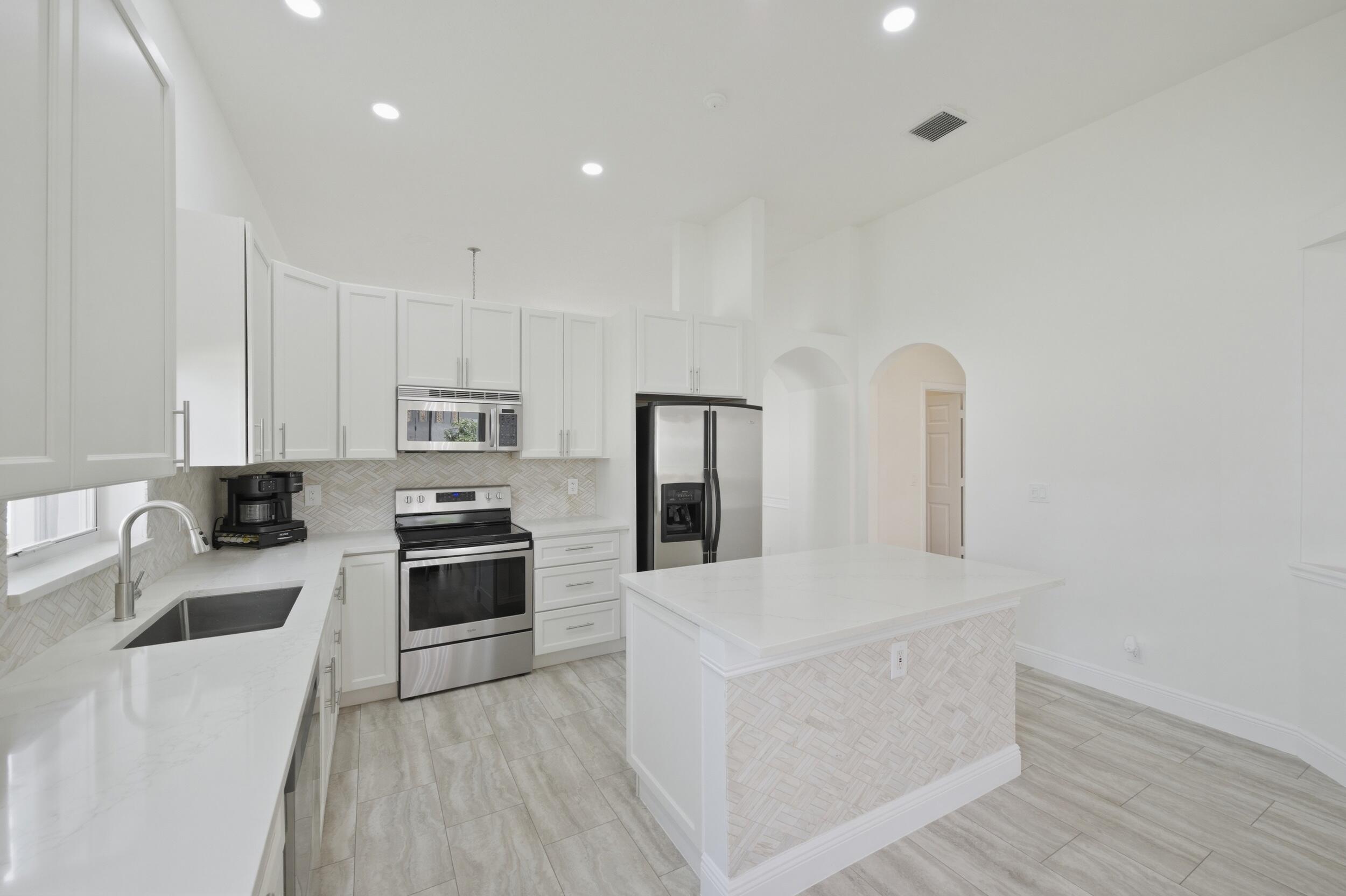 8534 Vía D Oro Boca Raton, FL 33433 - Photo 9 of 34 a kitchen with stainless steel appliances a stove top oven a sink a refrigerator and cabinets