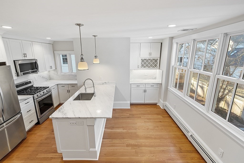 29 Central Street, Unit 2 Manchester, MA 01944 - Photo 11 of 22 a kitchen with granite countertop a stove top oven a sink dishwasher a dining table and chairs with wooden floor