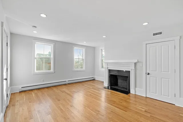 a kitchen with stainless steel appliances granite countertop a refrigerator a sink dishwasher a stove and white cabinets with wooden floor