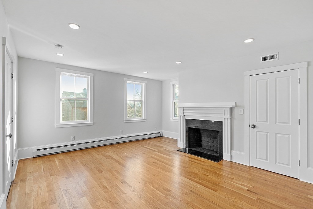 29 Central Street, Unit 2 Manchester, MA 01944 - Photo 3 of 22 an empty room with wooden floor fireplace and windows