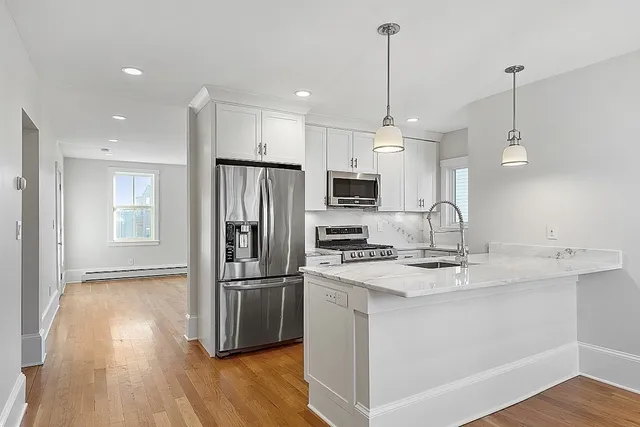 a kitchen with stainless steel appliances a sink a stove a refrigerator a center island with wooden floor