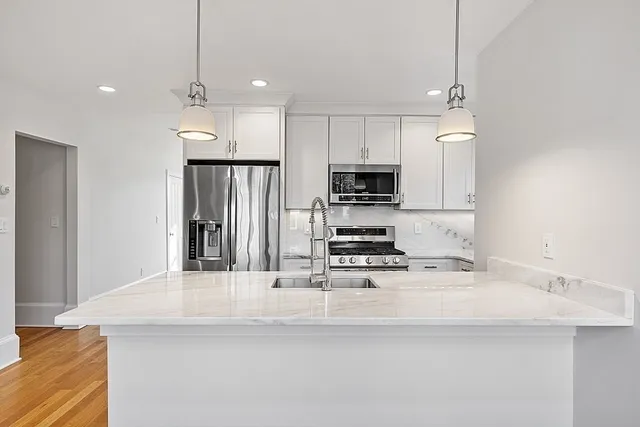 a kitchen with kitchen island white cabinets and stainless steel appliances