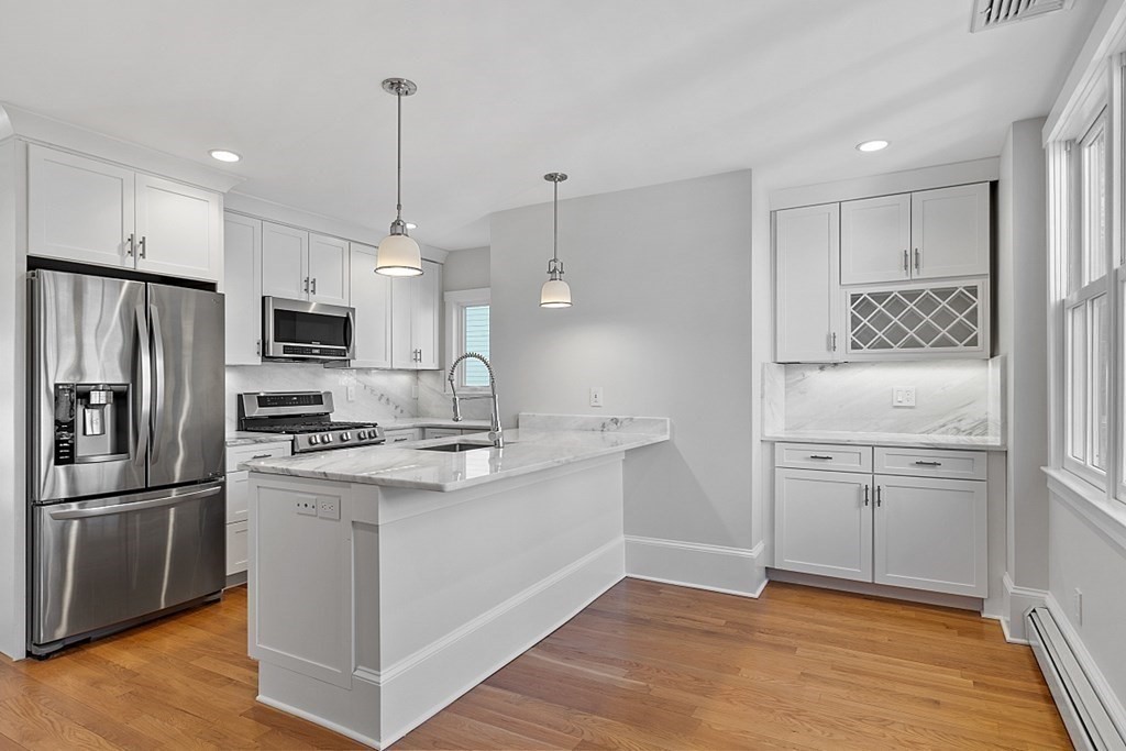 29 Central Street, Unit 2 Manchester, MA 01944 - Photo 6 of 22 a kitchen with kitchen island white cabinets and stainless steel appliances