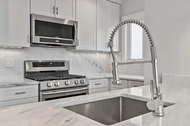 a kitchen with stainless steel appliances granite countertop a refrigerator a stove and a sink with wooden floor