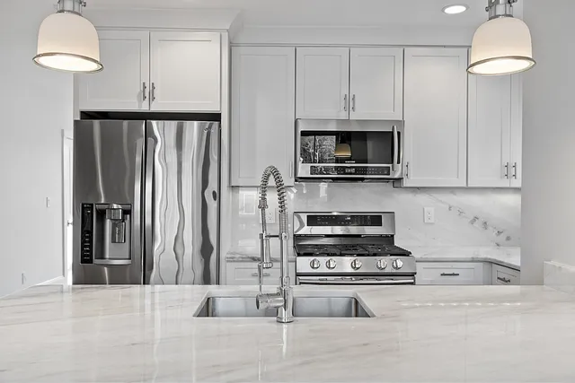 a kitchen with granite countertop a stove top oven a sink dishwasher a dining table and chairs with wooden floor