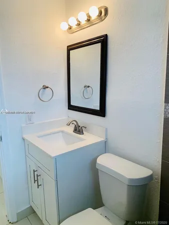 a bathroom with a toilet sink vanity and mirror