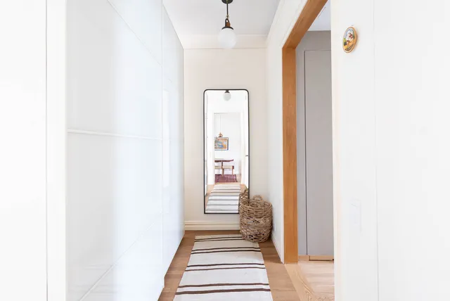 a view of a hallway with wooden floor and a carpet