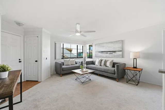 a living room with furniture and a large window with kitchen view