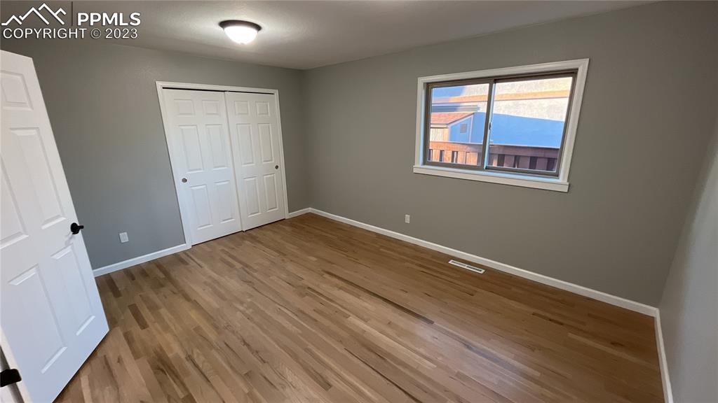 1219 Prairie Road Colorado Springs, CO 80909 - Photo 12 of 16 a view of an empty room with wooden floor and a window