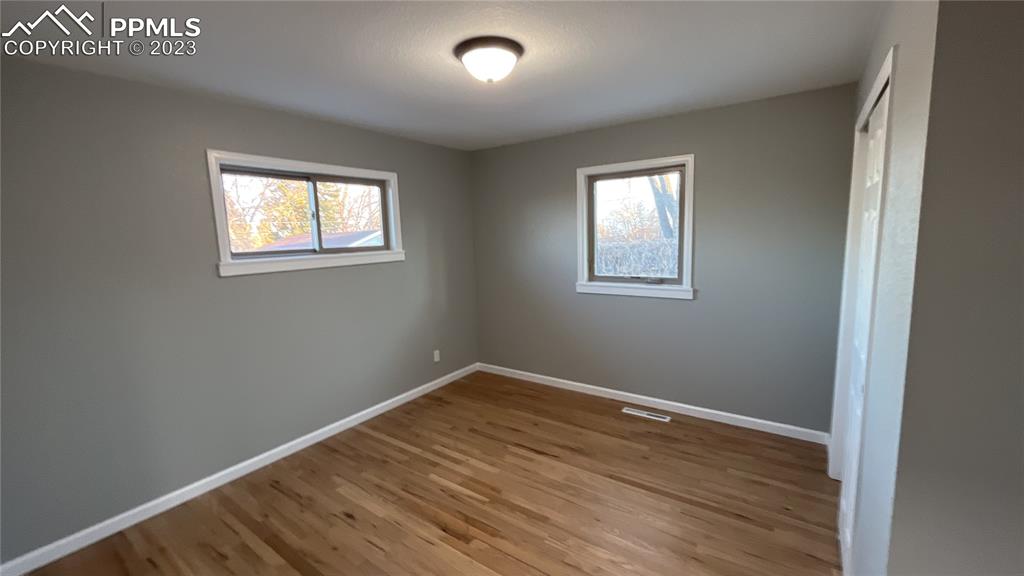 1219 Prairie Road Colorado Springs, CO 80909 - Photo 14 of 16 an empty room with wooden floor and windows