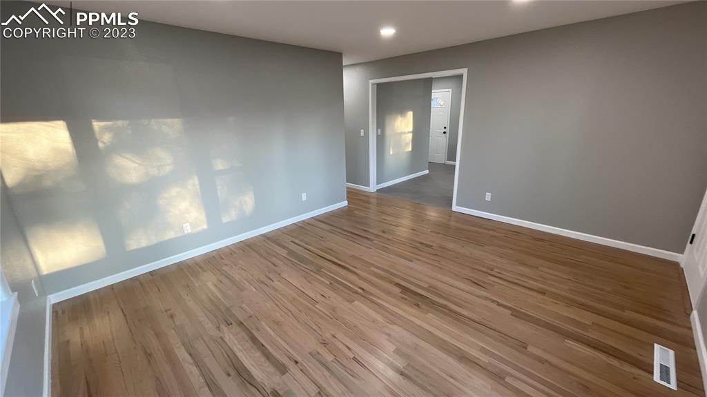 1219 Prairie Road Colorado Springs, CO 80909 - Photo 6 of 16 a view of an empty room with wooden floor and a window