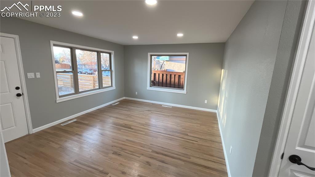 1219 Prairie Road Colorado Springs, CO 80909 - Photo 7 of 16 an empty room with wooden floor and windows