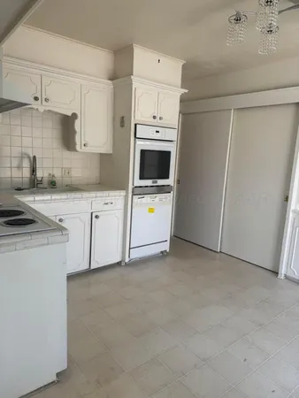 a kitchen with granite countertop white cabinets and white appliances
