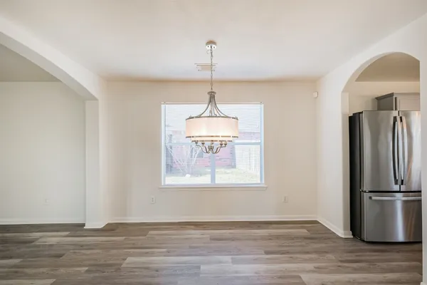a view of an empty room with window and wooden floor