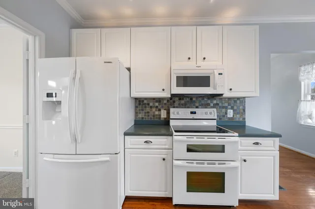 a kitchen with granite countertop white cabinets and stainless steel appliances