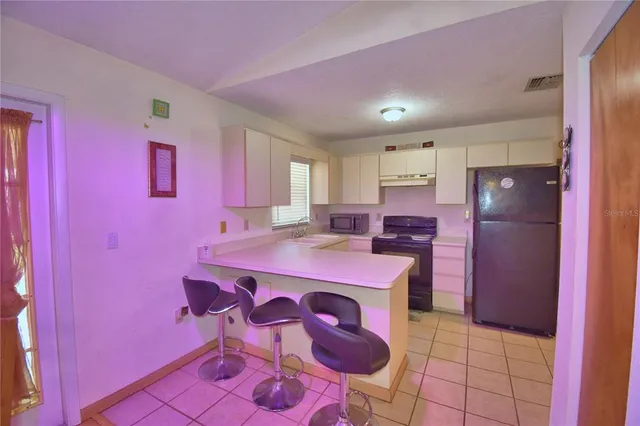 a kitchen with a table chairs refrigerator and a stove