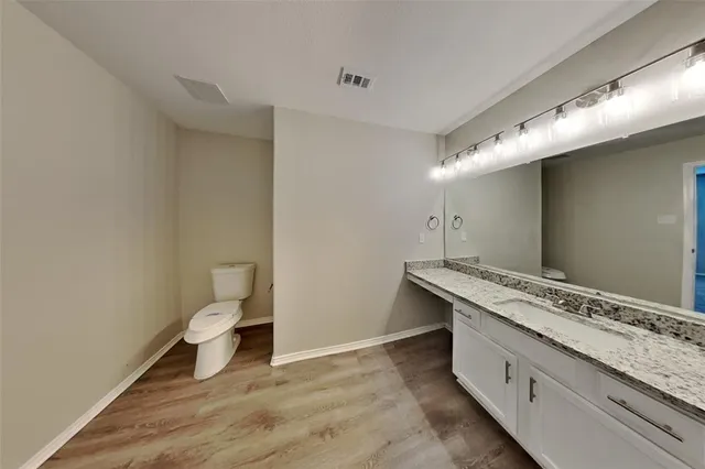 a bathroom with a granite countertop sink and a toilet