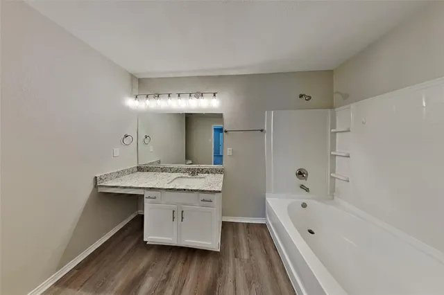 a bathroom with a granite countertop sink a mirror and bathtub