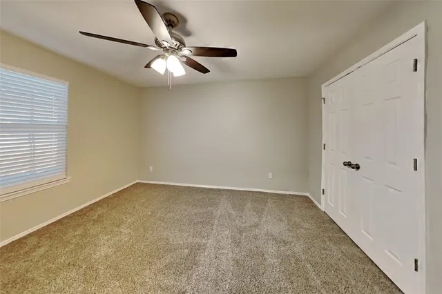 an empty room with a window and a fan