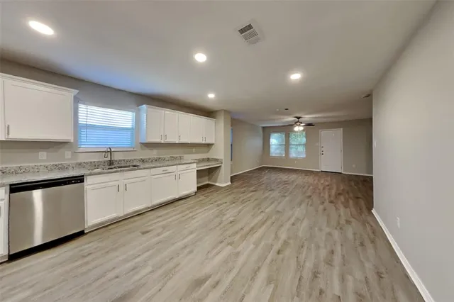 a large kitchen with a lot of white cabinets and wooden floor