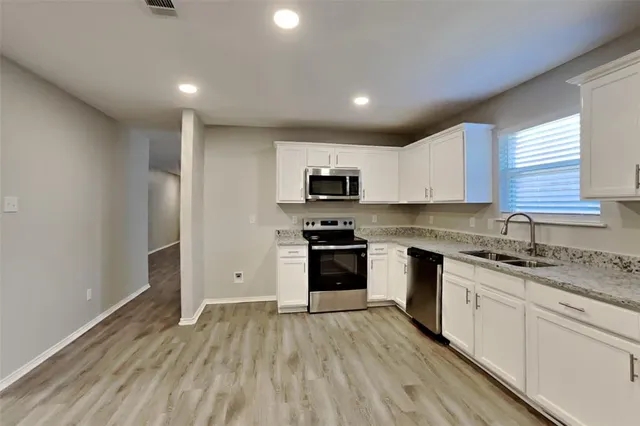 a kitchen with granite countertop a sink cabinets and stainless steel appliances