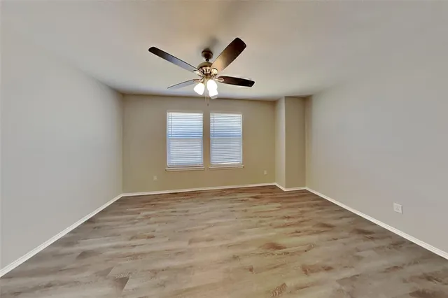an empty room with windows and ceiling fan