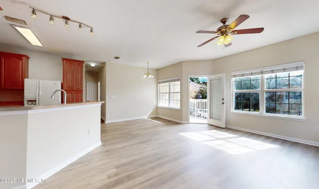 a view of an empty room with window and wooden floor