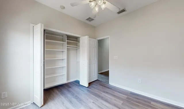 a view of an empty room with a window and wooden floor