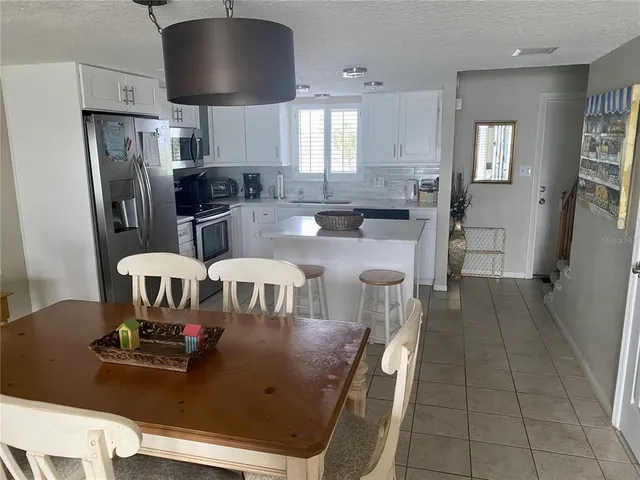 a kitchen with stainless steel appliances granite countertop a stove a refrigerator a sink a dining table and chairs