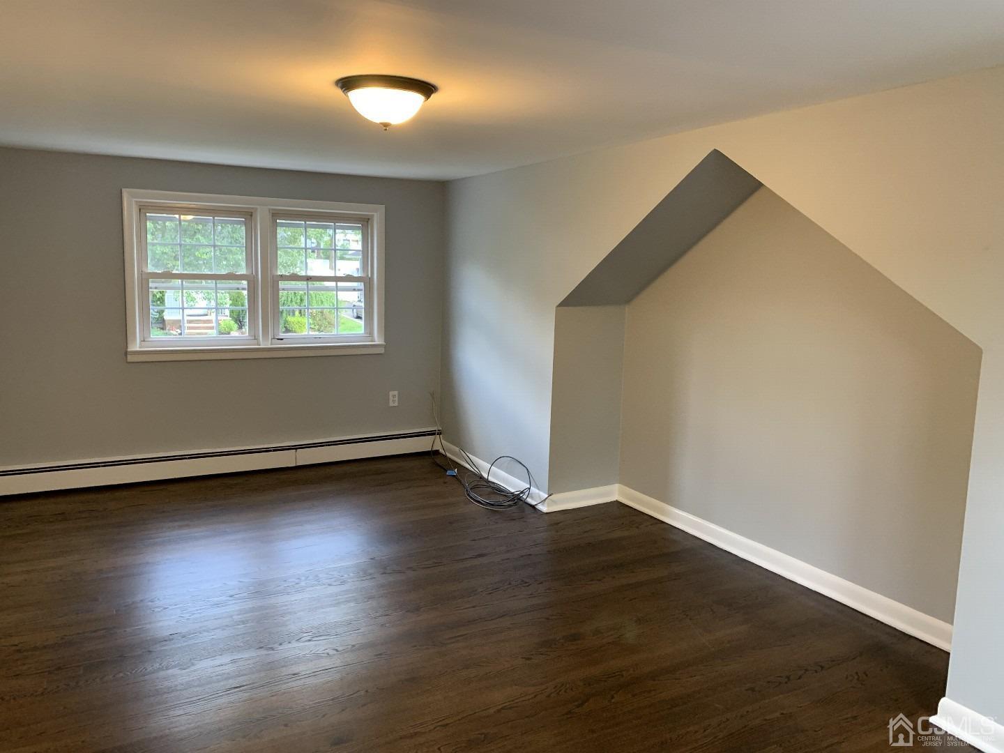 180 East Cliff Road Colonia, NJ 07067 - Photo 5 of 6 a view of an empty room with wooden floor and a window