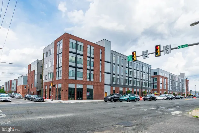 a front view of a building with lot of cars and trees