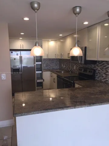 a large kitchen with a refrigerator a fireplace and a counter top