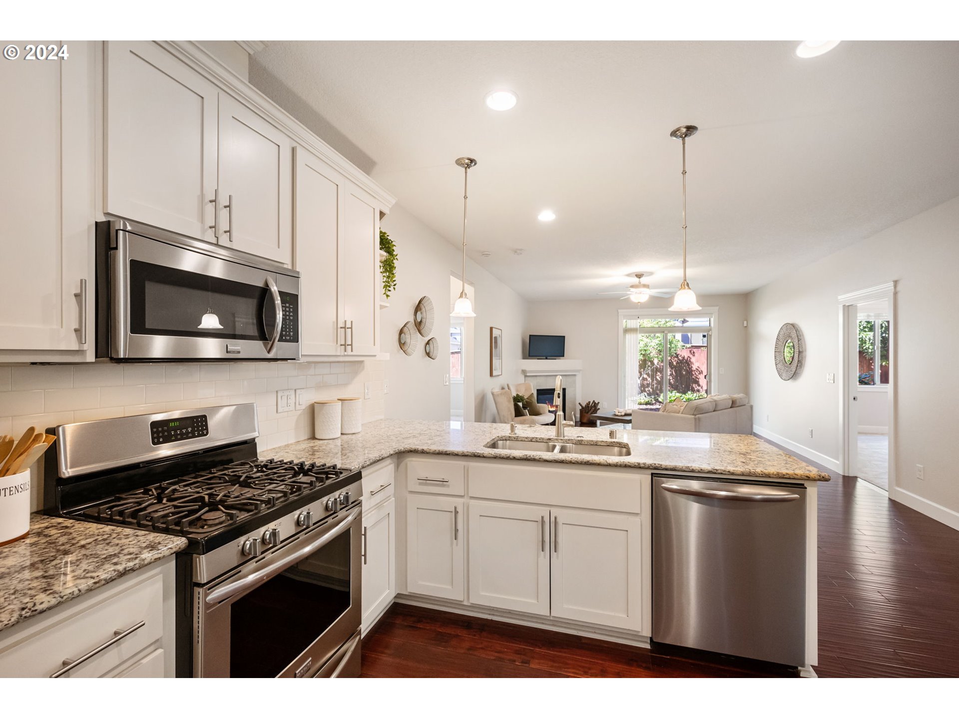 151 North 40th Avenue Ridgefield, WA 98642 - Photo 13 of 42 a kitchen with stainless steel appliances kitchen island granite countertop a stove a sink dishwasher and white cabinets with wooden floor