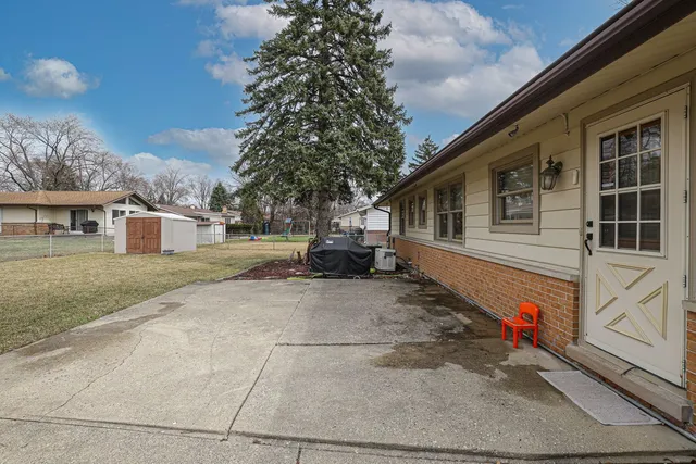 a view of a house with a small yard and a large tree