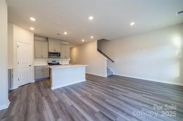 a view of kitchen with cabinets stainless steel appliances and wooden floor