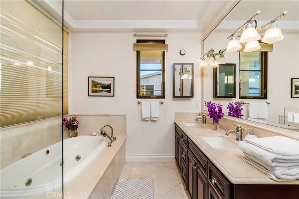 a bathroom with a granite countertop tub double vanity sink and a large mirror
