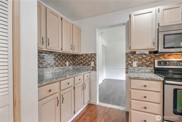 a kitchen with granite countertop white cabinets and stainless steel appliances