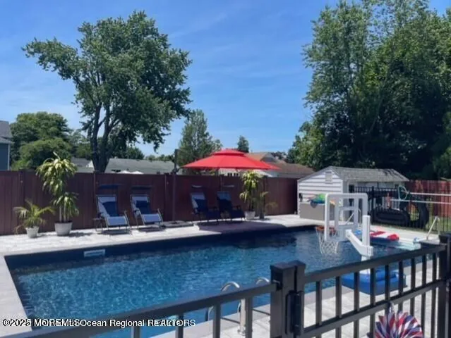 a view of a patio with table and chairs under an umbrella with large trees