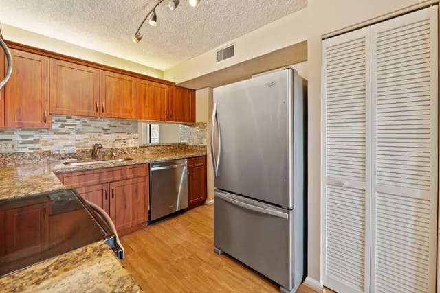 a kitchen with stainless steel appliances granite countertop a refrigerator a sink and a stove