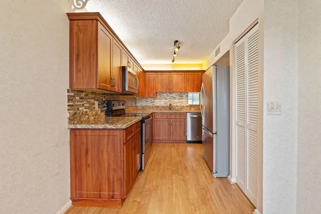 a kitchen with stainless steel appliances granite countertop a stove a sink dishwasher and a refrigerator