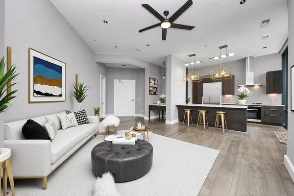 a living room with furniture kitchen view and a wooden floor