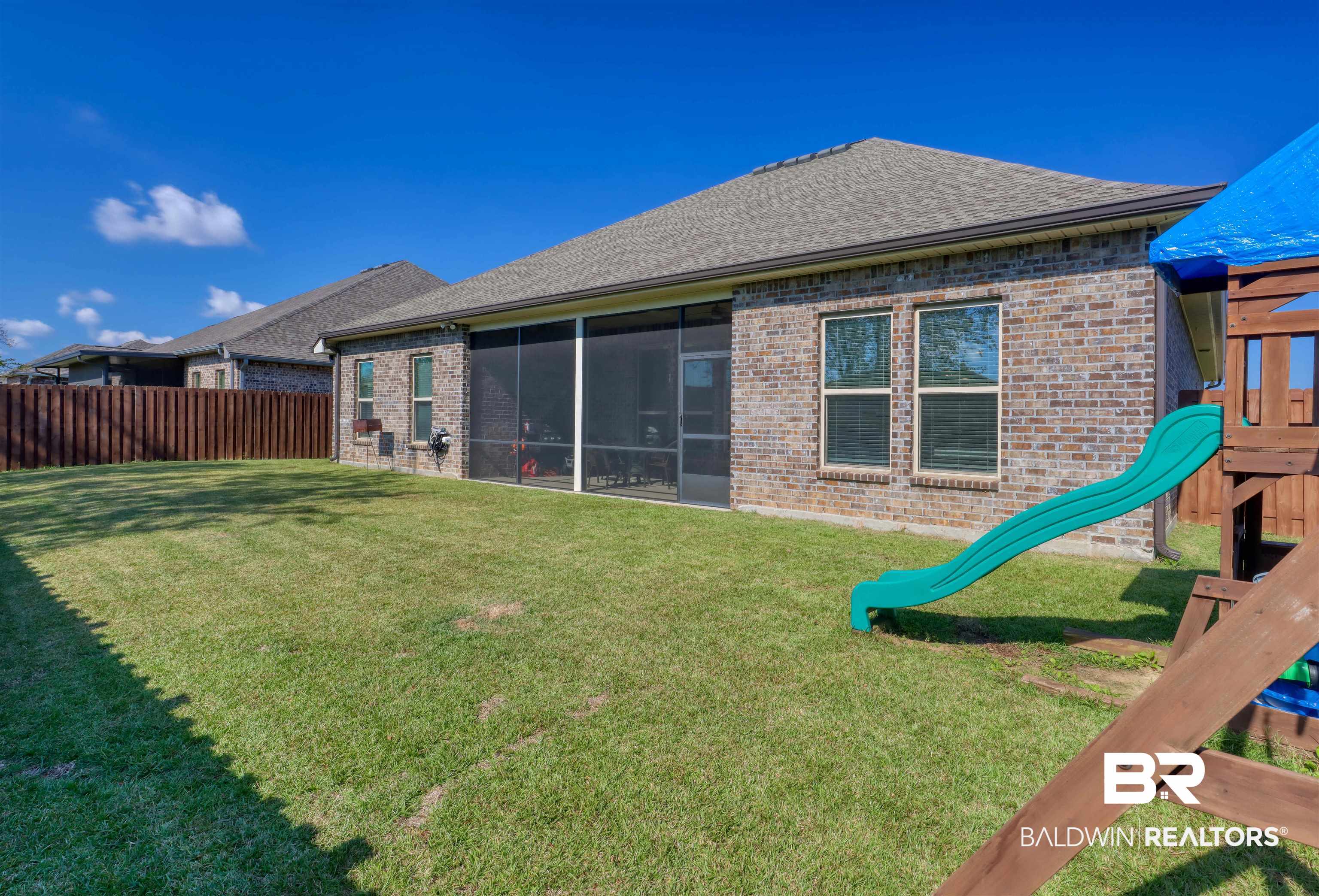 992 Dalton Circle Foley, AL 36535 - Photo 23 of 28 Rear view of property with a playground, brick siding, a sunroom, roof with shingles, and a fenced backyard