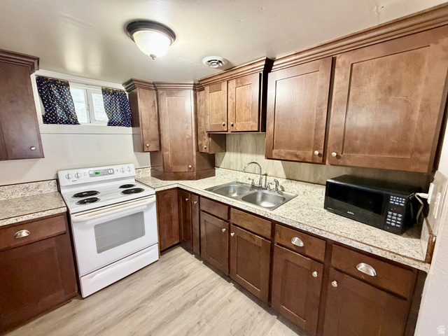7 Foothill Boulevard Pocatello, ID 83204 - Photo 2 of 13 Kitchen featuring wood-finish cabinetry, light-toned countertops, a stainless steel double basin sink, and wood-finish flooring