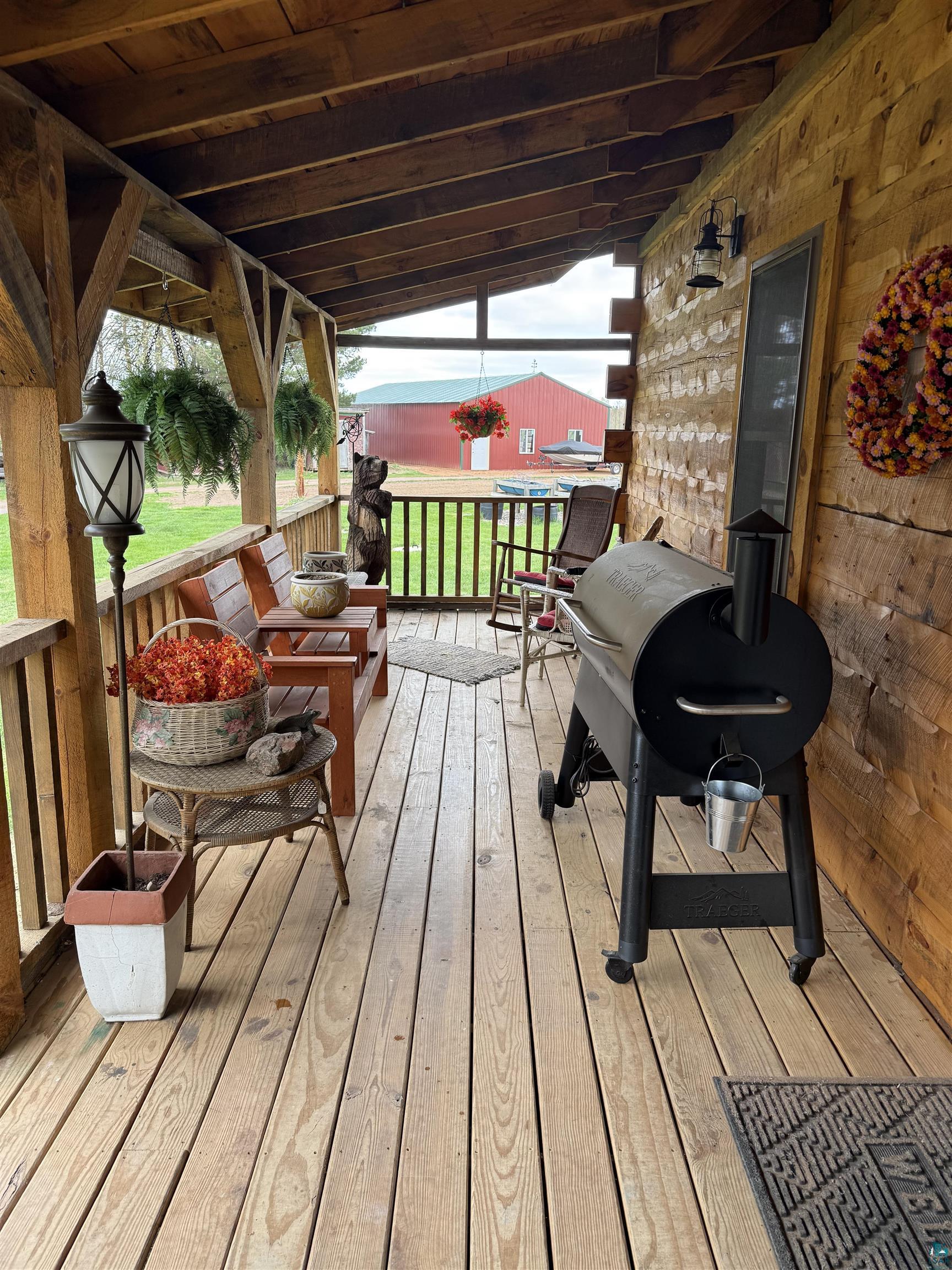 37590 Degerstrom Road Askov, MN 55704 - Photo 31 of 53 Covered porch featuring wood-finish flooring, exposed beam ceiling, wood railing, and rustic wall siding