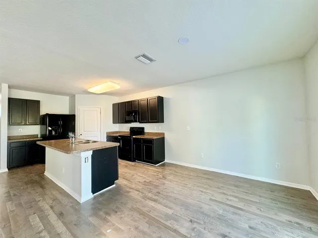 a living room with furniture a flat screen tv and kitchen view