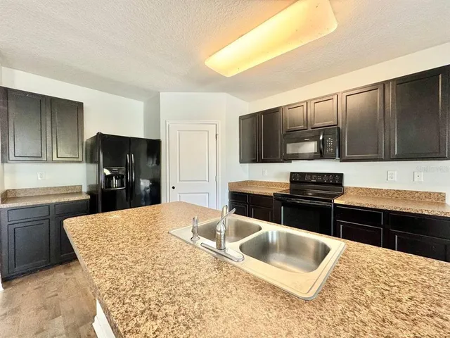 a kitchen with stainless steel appliances kitchen island granite countertop a sink dishwasher stove and refrigerator